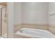 Bathroom featuring large soaking tub and glass enclosed shower with neutral tiling at 6528 Sedgeford Dr, Lakeland, FL 33811