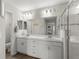 Bright bathroom with double vanity, large mirror, white cabinetry, and a glass-enclosed shower at 716 Vittorio Dr, Winter Haven, FL 33884