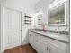 Bathroom featuring dual sinks, granite countertops, framed mirrors, and shelving at 7714 Chase Rd, Lakeland, FL 33810