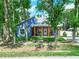 Blue home with a spacious porch, wooden beams, and a welcoming facade nestled among mature trees at 7714 Chase Rd, Lakeland, FL 33810