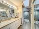 Bright bathroom with a marble countertop vanity, a glass shower, and a skylight at 8640 Firestone Cir, Clermont, FL 34711