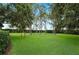 Wide view of the lush green backyard with mature trees creating a serene and private space at 105 Woden Way, Winter Haven, FL 33884