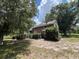Exterior angle showing a charming home nestled amid lush, mature trees and vibrant, green foliage at 1805 S Lake Reedy Blvd, Frostproof, FL 33843