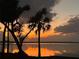 Scenic waterfront view featuring a vibrant sunset over a tranquil lake, with palm trees silhouetted at 1805 S Lake Reedy Blvd, Frostproof, FL 33843