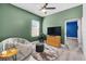 Cozy bedroom with gray wood floors, green walls, ceiling fan, and a sitting area with a large gray beanbag chair at 185 St Thomas Dr, Mulberry, FL 33860
