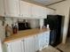 Cozy kitchen featuring white cabinets, oak countertops, and a modern black refrigerator at 1976 Holy Cow Rd, Polk City, FL 33868