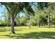 Expansive lot features lush green grass, tall trees, and a classic wood fence under a beautiful blue sky at 1976 Holy Cow Rd, Polk City, FL 33868