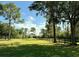 Expansive lot features lush green grass, tall trees, and a classic wood fence under a beautiful blue sky at 1976 Holy Cow Rd, Polk City, FL 33868