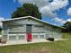 Metal outbuilding for sale with multiple sliding doors, concrete base, and a lush green lawn at 1976 Holy Cow Rd, Polk City, FL 33868