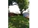 Landscaped backyard featuring a lush green lawn, mature trees, a wooden fence, and a storage shed with a deck at 2021 Oliver Pl, Winter Haven, FL 33881