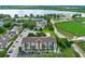 Aerial view of a condo community showcasing a pool, sports field, lush greenery, and lake in the background at 2037 San Marcos Se Dr # 443, Winter Haven, FL 33880