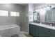 A bathroom with a marble shower, tub, double sinks and blue cabinets at 209 Andros Ave # 15301, Davenport, FL 33897