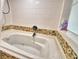 Clean, white tiled bathtub with jacuzzi jets and decorative mosaic tile accents at 2252 Fox Run Rd, Lake Wales, FL 33898