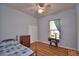 Cozy bedroom with wooden floors, a ceiling fan, and a window with a blue curtain at 2252 Fox Run Rd, Lake Wales, FL 33898
