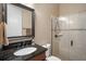 Bathroom vanity with granite countertop, dark cabinets, framed mirror, and tiled shower with glass doors at 2977 Sequoyah Dr, Haines City, FL 33844