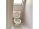 Narrow bathroom featuring a toilet, tile floors, and a window for natural light at 300 E Washington St, Minneola, FL 34715