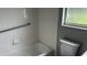This bathroom includes a white tiled shower and bath, grab bar, toilet, and window at 300 E Washington St, Minneola, FL 34715