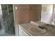 Bathroom features a marble countertop, white cabinets, framed mirror, and glass door shower at 300 E Washington St, Minneola, FL 34715