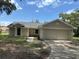 Charming single-story home featuring an attached two-car garage and a concrete driveway at 300 E Washington St, Minneola, FL 34715