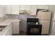 Functional kitchen featuring white cabinets, marble countertops, and black appliances at 300 E Washington St, Minneola, FL 34715