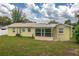 Exterior view of the rear of the home with a green lawn and an enclosed sunroom at 304 W Lake Ave, Auburndale, FL 33823