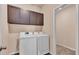 A well lit Laundry room featuring a washer, dryer, and overhead cabinets at 3173 Whispering Trails Ave, Winter Haven, FL 33884