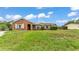 Charming brick home features a well-manicured lawn, crisp white shutters, and solar panels at 326 Sunset Rd, Frostproof, FL 33843