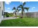 Well-maintained backyard with a brick patio, lush green lawn, and mature palm trees at 348 Lake Suzanne Dr, Lake Wales, FL 33859