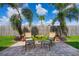 A cozy patio area features two chairs and a table, surrounded by palm trees and a wooden fence at 348 Lake Suzanne Dr, Lake Wales, FL 33859
