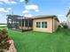 Well-maintained backyard with a screened lanai, green lawn, and exterior view of the home at 3802 Litchfield Loop, Lake Wales, FL 33859