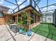 Outdoor seating on brick-patterned lanai with black frame, a view of the manicured lawn at 3802 Litchfield Loop, Lake Wales, FL 33859