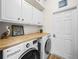 Laundry room featuring wood countertop, white cabinets, and front-loading washer and dryer at 3802 Litchfield Loop, Lake Wales, FL 33859