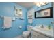 Light and bright bathroom with blue walls, a white vanity, toilet, and decorative framed mirror at 400 El Camino Dr # 201, Winter Haven, FL 33884