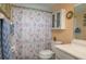 Bright bathroom featuring a toilet, vanity, storage cabinet and a shower with colorful patterned curtain at 400 El Camino Dr # 201, Winter Haven, FL 33884