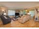 Spacious living room with wood floors, comfortable seating, and an adjoining enclosed porch at 400 El Camino Dr # 201, Winter Haven, FL 33884