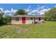 View of home's exterior back, featuring a bright red door and green yard at 407 Snively Ave, Winter Haven, FL 33880