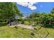 The backyard features a metal frame structure overgrown with greenery, set on a concrete base amid grassy surroundings at 407 Snively Ave, Winter Haven, FL 33880