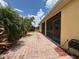 View of the brick paved patio outside of the screened in porch, with view of tropical landscaping at 4469 Turnberry Ln, Lake Wales, FL 33859