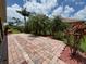 Brick patio area surrounded by lush tropical landscaping and palm trees, offering a serene outdoor space at 4469 Turnberry Ln, Lake Wales, FL 33859