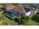 Aerial view of a home featuring a screened in pool enclosure and solar panels on the roof at 5340 Nicklaus Dr, Winter Haven, FL 33884