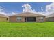 The home's rear exterior shows a screened lanai and an expansive yard for relaxation and recreation at 5751 Lakeside Landings Blvd, Winter Haven, FL 33881