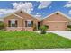 Inviting single-story home with a two-car garage, beautiful landscaping, and a welcoming entrance at 5751 Lakeside Landings Blvd, Winter Haven, FL 33881