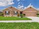 Single-story home featuring a well-manicured lawn, neutral color scheme, and attached two-car garage at 5751 Lakeside Landings Blvd, Winter Haven, FL 33881