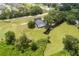 Aerial view of a home with a dark roof on a large, well-maintained lawn with scattered trees and a small creek at 5820 E Johnson Ave, Haines City, FL 33844