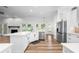 Modern open kitchen with white cabinets, stainless steel appliances, stone fireplace, and an island with a sink and counter space at 5820 E Johnson Ave, Haines City, FL 33844