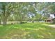 Spacious backyard with mature trees, grassy area, and a playset, perfect for outdoor fun at 6028 Hillside Heights Dr, Lakeland, FL 33812