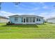 Backyard view of home featuring Florida room, well-kept lawn and landscaping at 6192 Magpie Dr, Lakeland, FL 33809