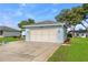 View of the two-car garage with a light blue exterior and well maintained lawn and landscaping at 6192 Magpie Dr, Lakeland, FL 33809