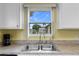 Bright kitchen sink overlooking a serene outdoor view with white cabinets and light countertops at 6192 Magpie Dr, Lakeland, FL 33809
