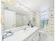Bright bathroom featuring floral wallpaper, a large mirror, and a well-lit vanity with white countertop at 700 Mirror Nw Ter # 702, Winter Haven, FL 33881